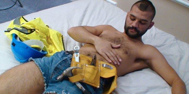 Hairy young construction worker cresses his chest