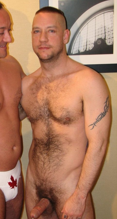 Beefy guy in a Canadian jockstrap poses with naked hairy guy with a pierced dick