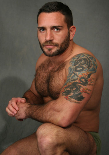 man with beard shows hairy chest and smoldering look