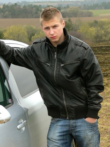 Cute blond twink in a leather jacket outside