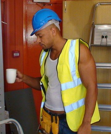 Contruction worker sips his coffee in his uniform