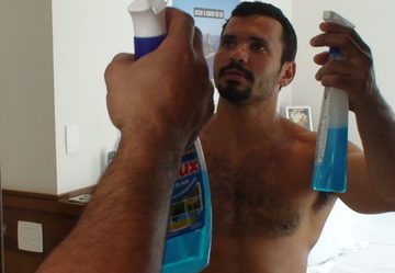 shirtless latin man with hairy chest cleans mirror
