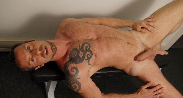 Sexy stud Rocco Banks lays naked on a workout bench