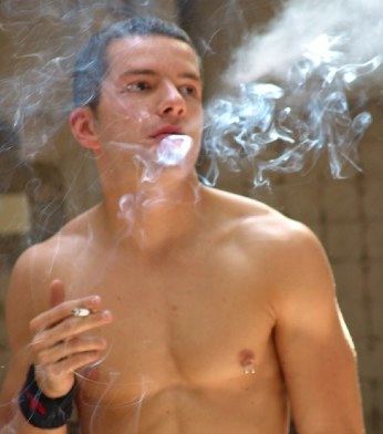 Young guy with pierced nipple smoking a cigarette