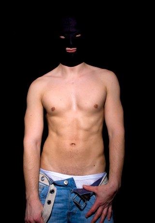 Smooth jock in mask takes off his pants