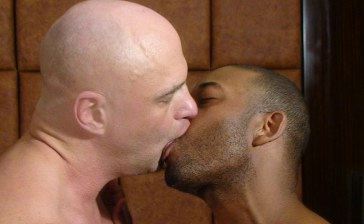 Bald white guy passionately kisses a black guy with a scruffy beard