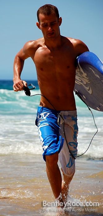 Hot surfer running through the surf with his board