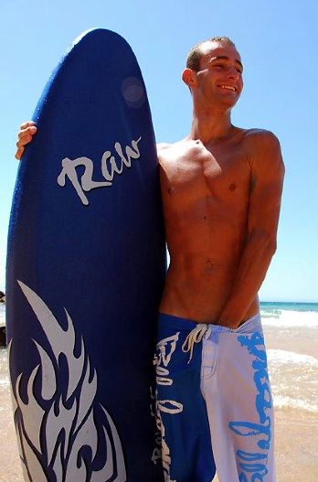Hot surfer dude with a "RAW" board and his hand down his pants