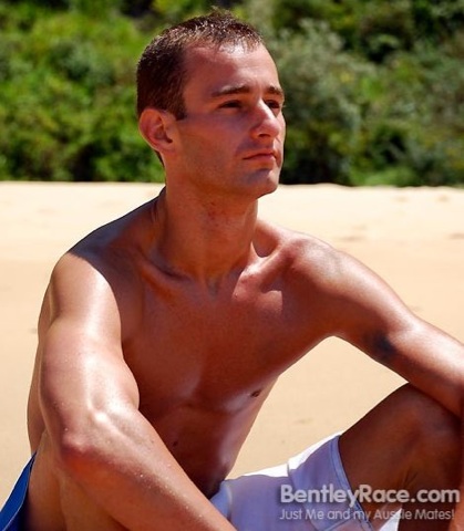 Hot skinny guy sitting on the beach with his shirt off
