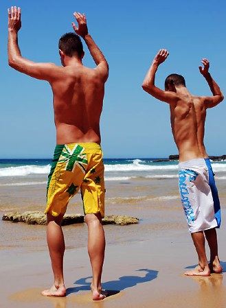 Two guys on the beach about to do hand stands