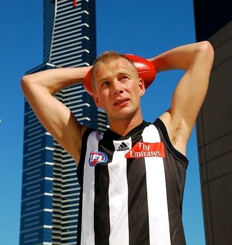 Hot blond jock poses in his uniform on a roof with a skyscraper in the background