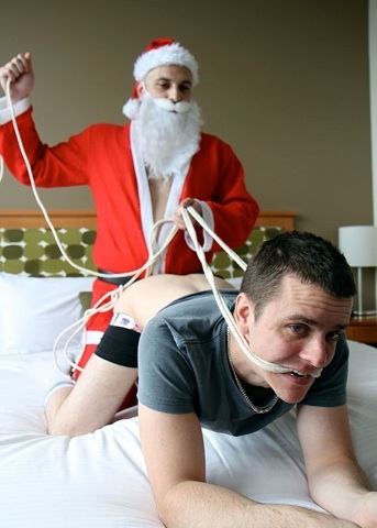 Santa Lukas Samson has Brent Tyler tied up on the bed