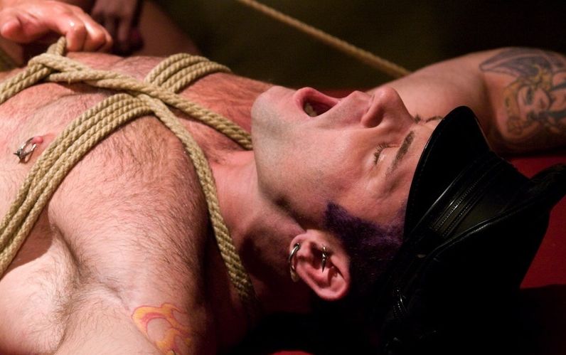 guy with pierced nipple and leather bound in ropes
