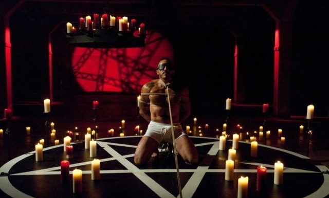 Alessio Romero blindfolded and tied up in a pentagram