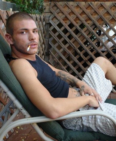 Scruffy punk kid smokes while grabbing his crotch