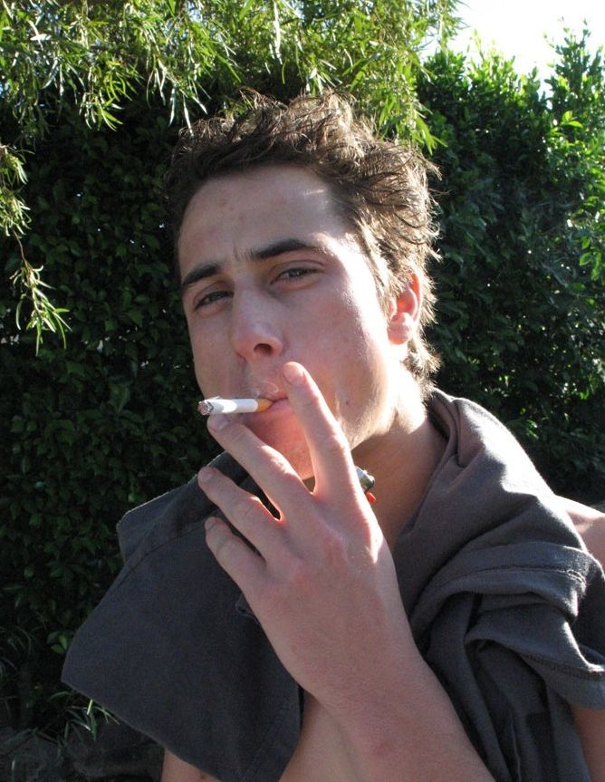 Dark haired twink smoking outside