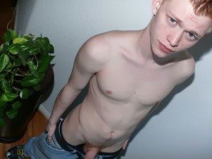 Teen with pale skin and red hair pulls down his pants and reveals his dick