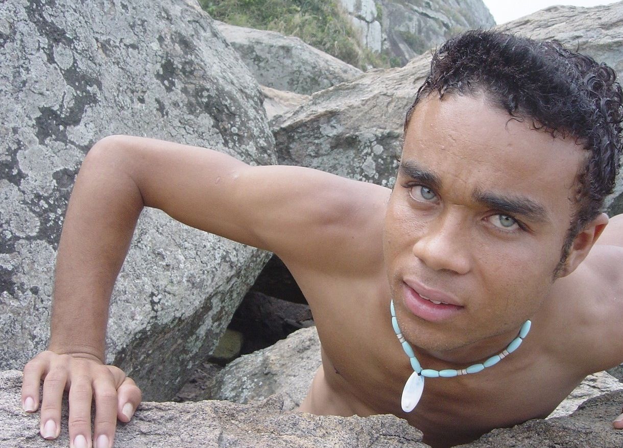 Young Latino climbing rocks