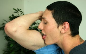 Dark haired young guy licking the bicep of a friend