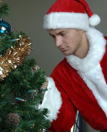 Jock boy dressed as Santa decorating a tree