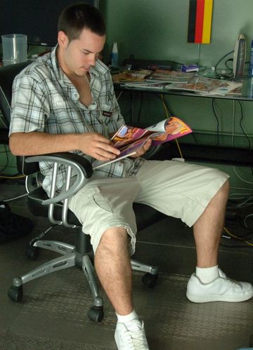 Guy sitting at his desk looking at porn magazines
