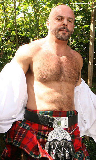 Hairy guy in a kilt taking off his shirt and showing his hairy chest