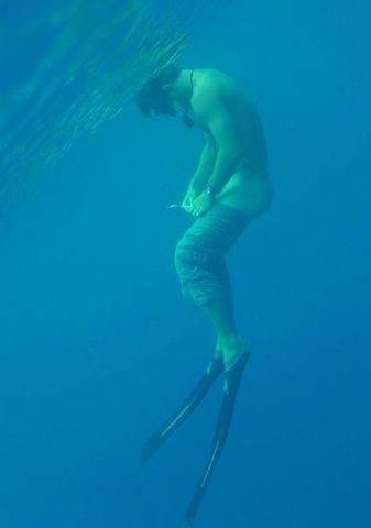 Young swimmer takes his trunks off underwater