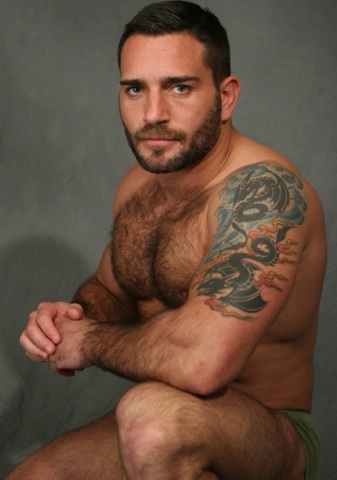 man with beard shows hairy chest and smoldering look