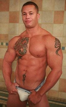 muscle hunk smiles and shows a bit of cock