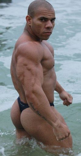 Hot bodybuilder in a thong in the surf at the ocean