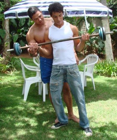 Thin young Latin boy gets a personal training session from his buff trainer outdoors