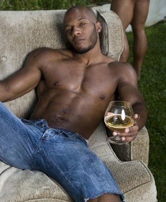 Hunky Black guy relaxes with a drink outside<br />
