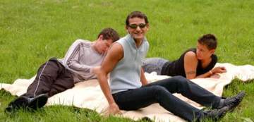 Three hot gay guys hanging out on a blanket in a field