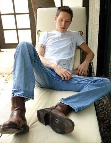 Twink in boots sits on chair